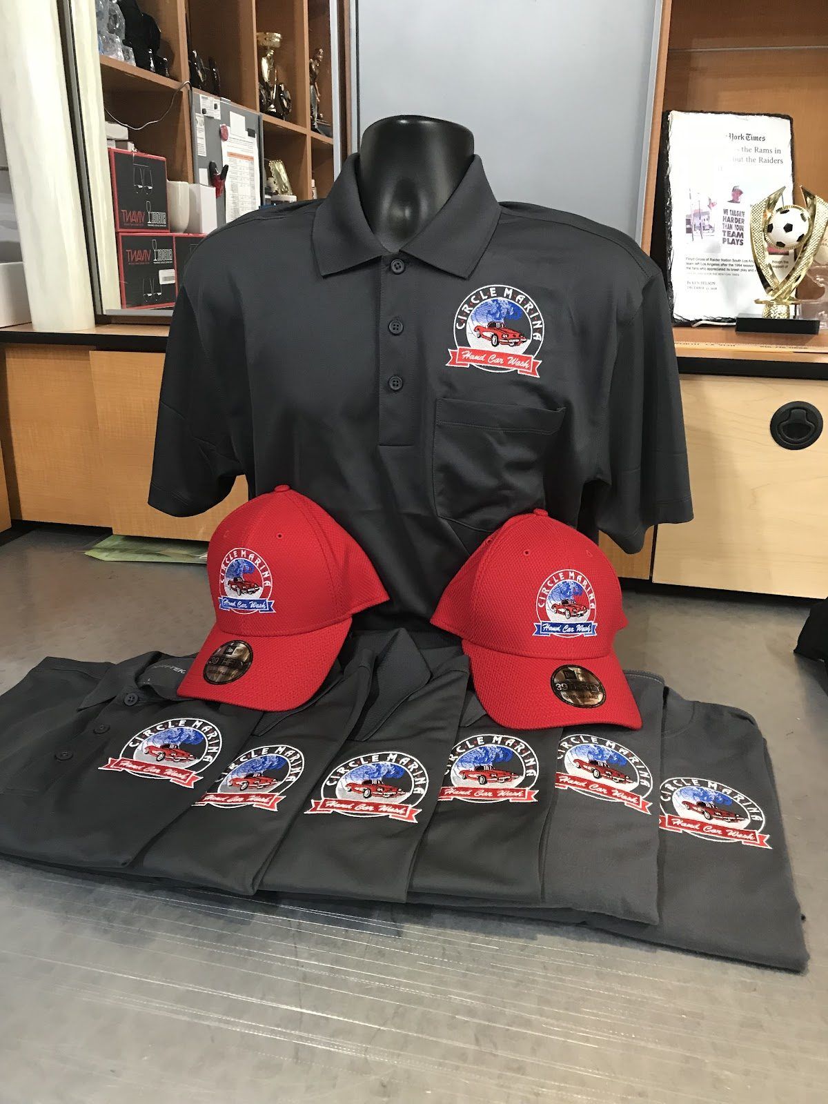 Charcoal polos and two red caps, each embroidered with a hand car wash’s round full-color logo