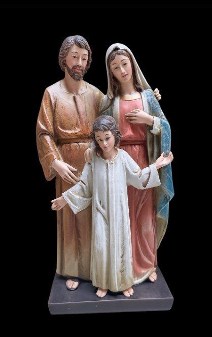 A painted Holy Family statue, Joseph and Mary behind the child Jesus, on a dark base